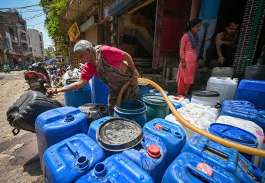 NEW DELHI, INDIA - 30 Mayıs 2024: 30 Mayıs 2024 'te Yeni Delhi, Hindistan' da Anand Parbat 'ta su krizi sırasında Delhi Jal Tahta Tankeri' nden su dolduran insanlar görüldü