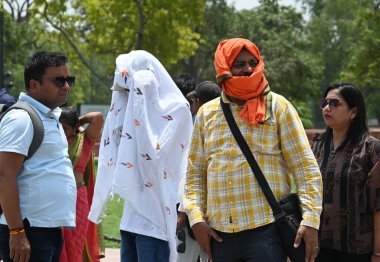 NEW DELHI, INDIA - 20 Mayıs 2024: Sıcak yaz mevsiminde Yeni Delhi, Hindistan 'da 20 Mayıs 2024' te Kartvaya Yolu çimlerinde sıcak hava dalgasına göğüs geren ziyaretçiler.