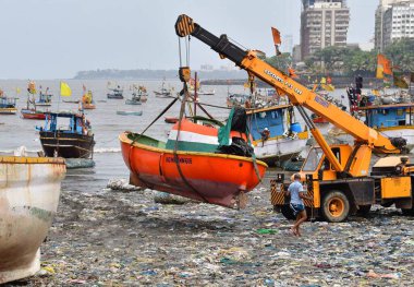 MUMBAI, INDIA - 27 Mayıs 2024 'te Hindistan' ın Mumbai kentindeki Badhwar Park 'ta, bir vinç kullanılarak deniz kıyısından çıkarılan bir tekne..