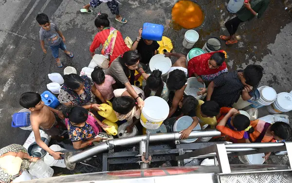 NEW DELHI, INDIA - 29 Mayıs 2024 'te Hindistan' ın Yeni Delhi kentindeki Sanjay Camp Chanakyapuri 'de yaz aylarında yaşanan bir su krizi sırasında, yerliler bir tankerden içme suyu alıyorlar. Artan sıcaklıkla Delhi büyük bir su kriziyle karşı karşıya.