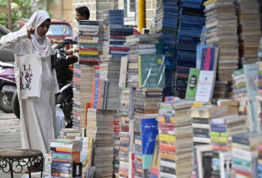 MUMBAI, INDIA - 23 Nisan 2024: Genç İncil-sever, 23 Nisan 2024 'te Hindistan' ın Mumbai kentinde Fort Book ve Telif Hakları Günü münasebetiyle sokak satıcıları tezgahındaki kitapları kontrol eder. Fotoğraf: Anshuman Poyrekar / Hindustan Times)