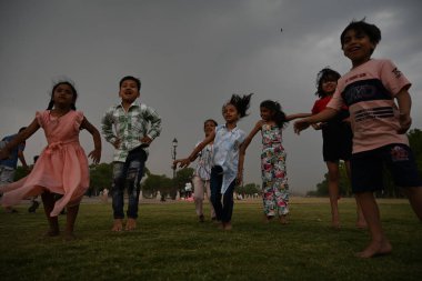 NEW DELHI, INDIA - APRIL 13, 2024: Children enjoy cloudy and raining weather at Kartavya Path, on April 13, 2024 in New Delhi, India. IMD said that due to the influence of several weather systems, including an intense western disturbance. clipart