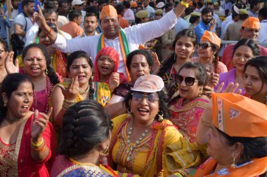 GHAZIABAD, INDIA - 6 Nisan 2024 'te Gaziabad Ambedkar Yolu' nda BJP 'nin yol göstericileri, Hindistan' ın Gaziabad kentinde dans edip şarkı söyleyen kadın işçiler. Parti sembolü 'lotus' u tutan Başbakan Modi tezahürat yapan kalabalığa el salladı 