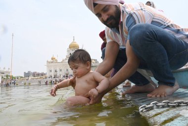 NEW DELHI, INDIA - APRIL 13, 2024: Devotees take a dip in the sacred pond of Gurudwara Bangla Sahib on the occasion of Baisakhi festival, on April 13, 2024 in New Delhi, India. Baisakhi or Vaisakhi, a popular spring festival. clipart