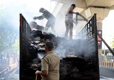 NOIDA, INDIA - 7 Nisan 2024 Noida, Hindistan 'da, Noida City Center metro istasyonu yakınlarındaki bir karton kutuyla dolu bir kamyonda yangını söndüren itfaiye personeli. 