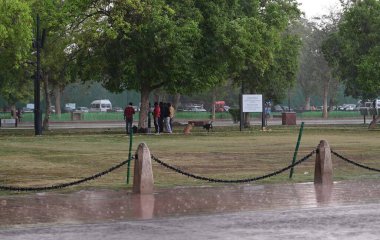 NEW DELHI, INDIA - 13 Nisan 2024 'te Yeni Delhi, Hindistan' da Kartavaya Yolu 'nda bulutlar ve güçlü rüzgar esintisi eserken ziyaretçiler görülüyor. IMD, çeşitli hava sistemlerinin etkisinden dolayı