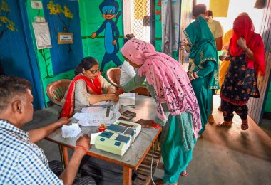 MUZAFFARNAGAR, INDIA - 19 Nisan 2024 tarihinde Muzaffarnagar 'da yapılan bir sandık merkezinde Lok Sabha' nın Birinci Aşaması seçimlerinde oy kullanmak için gelen parmak seçmenlerini mürekkeple işaretleyen seçim memurları, 