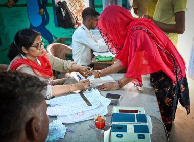 MUZAFFARNAGAR, INDIA - 19 Nisan 2024 tarihinde Muzaffarnagar 'da yapılan bir sandık merkezinde Lok Sabha' nın Birinci Aşaması seçimlerinde oy kullanmak için gelen parmak seçmenlerini mürekkeple işaretleyen seçim memurları, 
