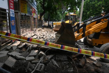 NEW DELHI, INDIA - JULY 29, 2024: Police personnel guard as a bulldozer demolishes parts of the IAS coaching institute in Old Rajinder Nagarafter three civil services aspirants died at a coaching centre due to drowning. clipart