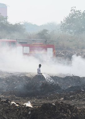 NOIDA, INDIA - 27 Mart 2024: İtfaiyeciler Sektör 32 'deki çöplük bahçesinde yangın söndürmeye çalışıyorlar. Pazartesi günü saat 18.00 sularında başlayan yangın, 32. Sektör 'de yaklaşık 1,5 km genişliğinde ve 2 km uzunluğunda bir alanı sardı.