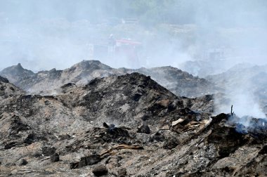 NOIDA, INDIA - 27 Mart 2024: İtfaiyeciler Sektör 32 'deki çöplük bahçesinde yangın söndürmeye çalışıyorlar. Pazartesi günü saat 18.00 sularında başlayan yangın, 32. Sektör 'de yaklaşık 1,5 km genişliğinde ve 2 km uzunluğunda bir alanı sardı.