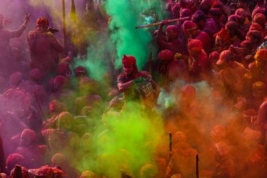 MATHURA, INDIA - 19 Mart 2024: İnsanlar 19 Mart 2024 tarihinde Hindistan 'ın Mathura kentinde Nandji Tapınağı' nda Lathmar Holi festivali sırasında birbirlerine renkli toz sürerler. 