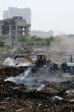 NOIDA, INDIA - 27 Mart 2024: İtfaiyeciler Sektör 32 'deki çöplük bahçesinde yangın söndürmeye çalışıyorlar. Pazartesi günü saat 18.00 sularında başlayan yangın, 32. Sektör 'de yaklaşık 1,5 km genişliğinde ve 2 km uzunluğunda bir alanı sardı.