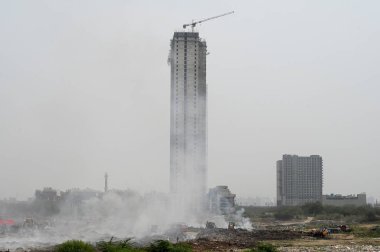 NOIDA, INDIA - 27 Mart 2024: İtfaiyeciler Sektör 32 'deki çöplük bahçesinde yangın söndürmeye çalışıyorlar. Pazartesi günü saat 18.00 sularında başlayan yangın, 32. Sektör 'de yaklaşık 1,5 km genişliğinde ve 2 km uzunluğunda bir alanı sardı.