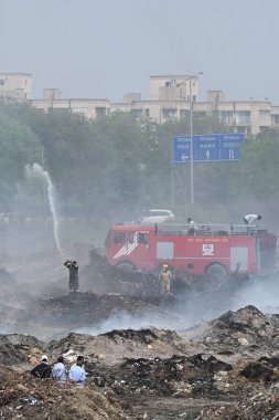 NOIDA, INDIA - 27 Mart 2024: İtfaiyeciler Sektör 32 'deki çöplük bahçesinde yangın söndürmeye çalışıyorlar. Pazartesi günü saat 18.00 sularında başlayan yangın, 32. Sektör 'de yaklaşık 1,5 km genişliğinde ve 2 km uzunluğunda bir alanı sardı.