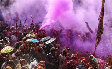 MATHURA, INDIA - 19 Mart 2024: İnsanlar 19 Mart 2024 tarihinde Hindistan 'ın Mathura kentinde Nandji Tapınağı' nda Lathmar Holi festivali sırasında birbirlerine renkli toz sürerler. 