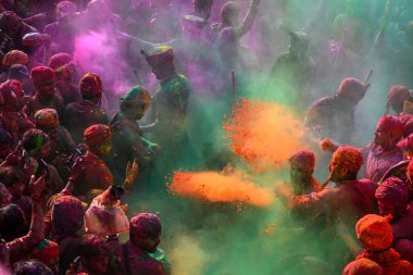 MATHURA, INDIA - 19 Mart 2024: İnsanlar 19 Mart 2024 tarihinde Hindistan 'ın Mathura kentinde Nandji Tapınağı' nda Lathmar Holi festivali sırasında birbirlerine renkli toz sürerler. 