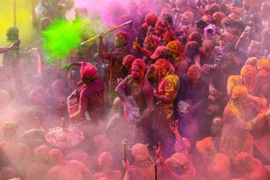 MATHURA, INDIA - 19 Mart 2024: İnsanlar 19 Mart 2024 tarihinde Hindistan 'ın Mathura kentinde Nandji Tapınağı' nda Lathmar Holi festivali sırasında birbirlerine renkli toz sürerler. 