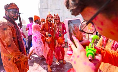 MATHURA, INDIA - 19 Mart 2024: İnsanlar 19 Mart 2024 tarihinde Hindistan 'ın Mathura kentinde Nandji Tapınağı' nda Lathmar Holi festivali sırasında birbirlerine renkli toz sürerler. 