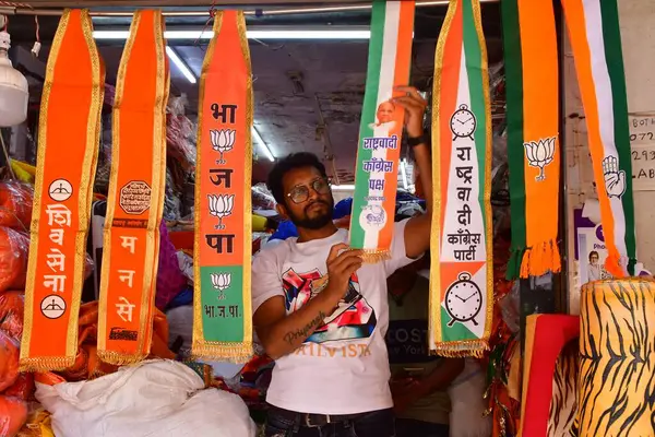 stock image MUMBAI, INDIA - MARCH 20, 2024: A man arranges scarves of political parties at a shop, ahead of Lok Sabha elections, at Lalbaug on March 20, 2024 in Mumbai, India. 