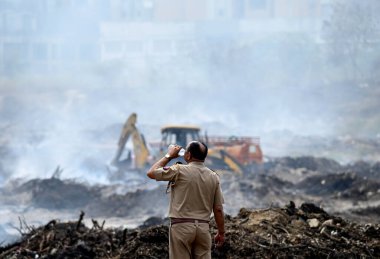 NOIDA, INDIA - 27 Mart 2024: İtfaiyeciler Sektör 32 'deki çöplük bahçesinde yangın söndürmeye çalışıyorlar. Pazartesi günü saat 18.00 sularında başlayan yangın, 32. Sektör 'de yaklaşık 1,5 km genişliğinde ve 2 km uzunluğunda bir alanı sardı.