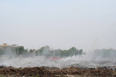 NOIDA, INDIA - 27 Mart 2024: İtfaiyeciler Sektör 32 'deki çöplük bahçesinde yangın söndürmeye çalışıyorlar. Pazartesi günü saat 18.00 sularında başlayan yangın, 32. Sektör 'de yaklaşık 1,5 km genişliğinde ve 2 km uzunluğunda bir alanı sardı.