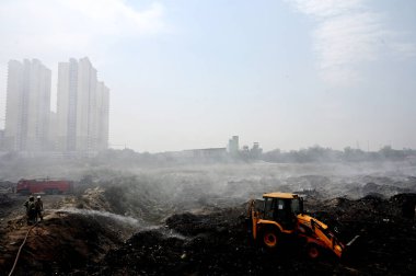 NOIDA, INDIA - 27 Mart 2024: İtfaiyeciler Sektör 32 'deki çöplük bahçesinde yangın söndürmeye çalışıyorlar. Pazartesi günü saat 18.00 sularında başlayan yangın, 32. Sektör 'de yaklaşık 1,5 km genişliğinde ve 2 km uzunluğunda bir alanı sardı.
