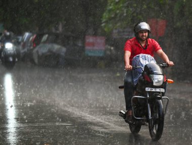 27 Temmuz 2024 'te, nemli bir yaz sonrasında, Hindistan' ın Noida kentinde akşam yağmuru sırasında dışarı çıkan banliyö sakinleri. 