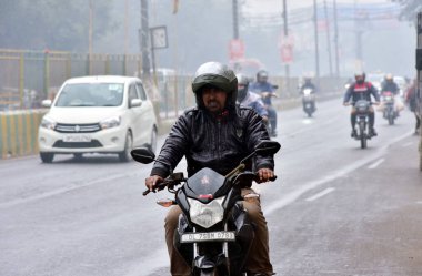 GHAZIABAD, INDIA - 31 Ocak 2024 'te Hindistan' ın Gaziabad kentindeki NH9 Dasna 'da bir hafif yağmur büyüsünün Gaziabad şehrini çarşamba gününden beri süpürmesiyle, banliyö sakinleri zorlu sürüş koşullarıyla karşı karşıya kaldı. Delhi 'de soğuk bir günde hafif yağmur vardı.