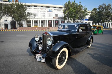 NEW DELHI, INDIA - FEBRUARY 11, 2024: Vintage cars make their way through a road as they participate during the 57th Statesman Vintage & Classic Car Rally at Connaught Place on February 11, 2024 in New Delhi, India. clipart