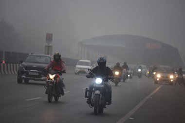 GURUGRAM, INDIA  JANUARY 24: Commuters seen wearing warm clothes while travel on Gurugram-Sohna elevated expressway amid cold and foggy winter morning near Air Force Station, on January 24, 2024 in Gurugram, India clipart