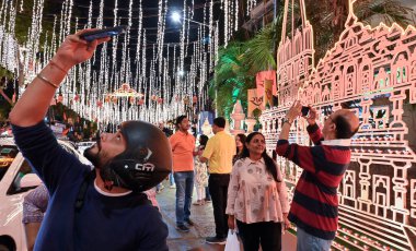 MUMBAI, INDIA - JANUARY 22, 2024: People take their selfie outside Ambani's house Antilia, which is illuminated on occasion of Lord Shri Ram Temple inauguration by PM Narendra Modi at Ayodhya, at Malabar Hills on January 22, 2024 in Mumbai, India. clipart