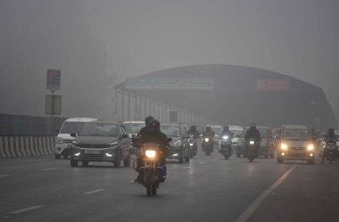 GURUGRAM, INDIA JANUARY 24: Gurugram-Sohna 'da seyahat ederken sıcak kıyafetler giydikleri görülen banliyö sakinleri, 24 Ocak 2024' te Hindistan 'ın Gurugram kentinde, Hava Üssü yakınlarındaki soğuk ve sisli kış sabahında ekspres yolda yükseldiler.