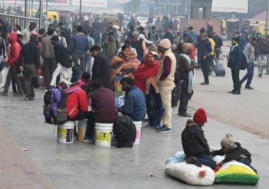 NEW DELHI, INDIA JANUARY 13, 2024: Yolcular Yeni Delhi Tren İstasyonu 'nda bir platformda oturuyorlar, yoğun sis nedeniyle çok sayıda tren servisi etkilendi