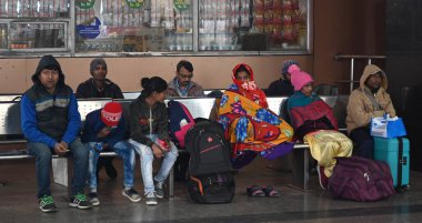NEW DELHI, INDIA JANUARY 13, 2024: Yolcular Yeni Delhi Tren İstasyonu 'nda bir platformda oturuyorlar, yoğun sis nedeniyle çok sayıda tren servisi etkilendi