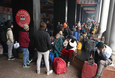 NEW DELHI, INDIA  JANUARY 13, 2024: Passengers sit on a platform at New Delhi Railway Station, several train services are impacted due to dense fog clipart