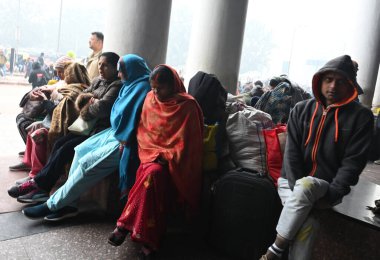 NEW DELHI, INDIA JANUARY 13, 2024: Yolcular Yeni Delhi Tren İstasyonu 'nda bir platformda oturuyorlar, yoğun sis nedeniyle çok sayıda tren servisi etkilendi