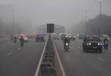 GURUGRAM, INDIA JANUARY 24: Gurugram-Sohna 'da seyahat ederken sıcak kıyafetler giydikleri görülen banliyö sakinleri, 24 Ocak 2024' te Hindistan 'ın Gurugram kentinde, Hava Üssü yakınlarındaki soğuk ve sisli kış sabahında ekspres yolda yükseldiler.