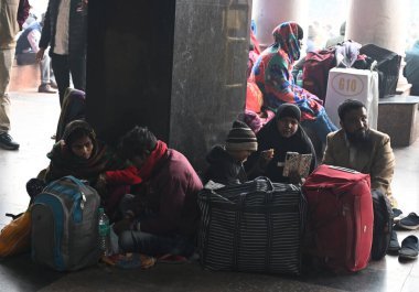 NEW DELHI, INDIA  JANUARY 13, 2024: Passengers sit on a platform at New Delhi Railway Station, several train services are impacted due to dense fog clipart