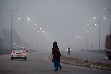 GURUGRAM, INDIA 11 HAZİRAN 2024: İnsanlar Umang Bhardwaj Chowk yakınlarında işe giderken sıcak kıyafetler giyerken görüldüler