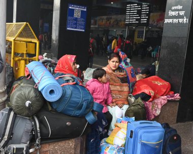 NEW DELHI, INDIA JANUARY 13, 2024: Yolcular Yeni Delhi Tren İstasyonu 'nda bir platformda oturuyorlar, yoğun sis nedeniyle çok sayıda tren servisi etkilendi