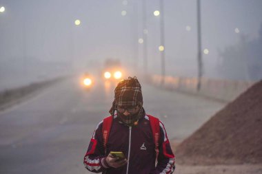 GURUGRAM, INDIA 11 HAZİRAN 2024: İnsanlar Umang Bhardwaj Chowk yakınlarında işe giderken sıcak kıyafetler giyerken görüldüler