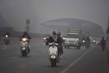 GURUGRAM, INDIA JANUARY 24: Gurugram-Sohna 'da seyahat ederken sıcak kıyafetler giydikleri görülen banliyö sakinleri, 24 Ocak 2024' te Hindistan 'ın Gurugram kentinde, Hava Üssü yakınlarındaki soğuk ve sisli kış sabahında ekspres yolda yükseldiler.