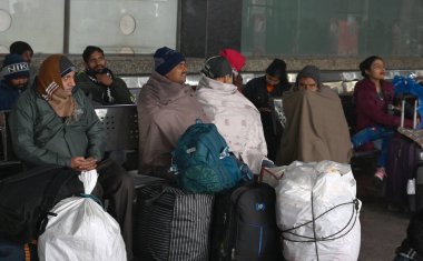 NEW DELHI, INDIA JANUARY 13, 2024: Yolcular Yeni Delhi Tren İstasyonu 'nda bir platformda oturuyorlar, yoğun sis nedeniyle çok sayıda tren servisi etkilendi