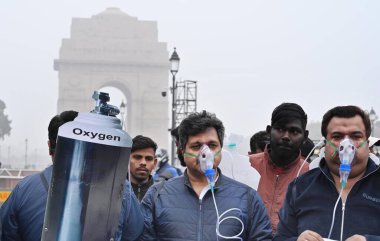 NEW DELHI, INDIA - 30 Aralık 2023 'te Hindistan Kapısı yakınında oksijen maskesi takan BJP çalışanları Delhi CM Arvind Kejriwal liderliğindeki eyalet hükümetine ve 30 Aralık 2023' te Yeni Delhi, Hindistan 'da hava kirliliğinin artmasına karşı protesto düzenlediler..  