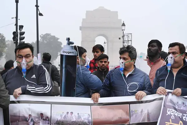 NEW DELHI, INDIA - 30 Aralık 2023 'te Hindistan Kapısı yakınında oksijen maskesi takan BJP çalışanları Delhi CM Arvind Kejriwal liderliğindeki eyalet hükümetine ve 30 Aralık 2023' te Yeni Delhi, Hindistan 'da hava kirliliğinin artmasına karşı protesto düzenlediler..  