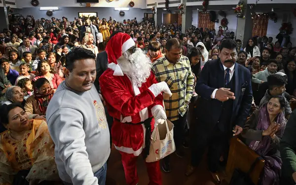 Stock image NEW DELHI, INDIA - DECEMBER 25, 2023: A man dressed as Santa Claus distributes candies during Christmas celebrations at Centenary Methodist Church, Lodhi Road, on December 25, 2023 in New Delhi, India.