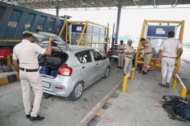 GURUGRAM, INDIA - AUGUST 27, 2023: Police personnel checking the vehicles going towards Nuh at Ghamroj toll plaza on Gurugram-Sohna road regarding Brij Mandal Yatra by Vishwa Hindu Parishad , on August 27, 2023 in Gurugram, India clipart