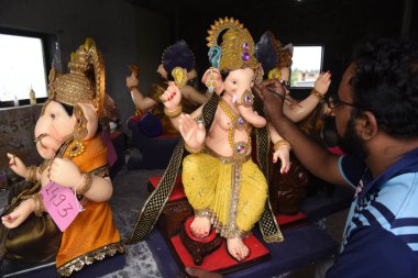 NAVI MUMBAI, INDIA - 8 Ağustos 2023 'te Hindistan' ın Navi Mumbai kentinde düzenlenen Pen 'de Ganesh Chaturthi festivali öncesinde Hindu tanrı Ganpati putlarına son rötuşları yapan bir köy hamur kalemi sanatçısı.
