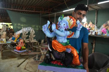 NAVI MUMBAI, INDIA - AUGUST 8: A village hamrapur Pen artist giving finishing touches to Hindu God Ganpati idols ahead Ganesh Chaturthi festival at Pen  on August 8, 2023 in Navi Mumbai, India. clipart